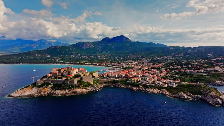 Vista aérea de drone sobre a cidade histórica de Calvi, Córsega, França. Vista pitoresca da cidade costeira, paisagem, nuvens fofas e montanhas ao fundo