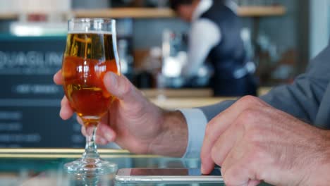 Man-tasting-wine-an-touching-his-smartphone-in-front-of-the-waiter