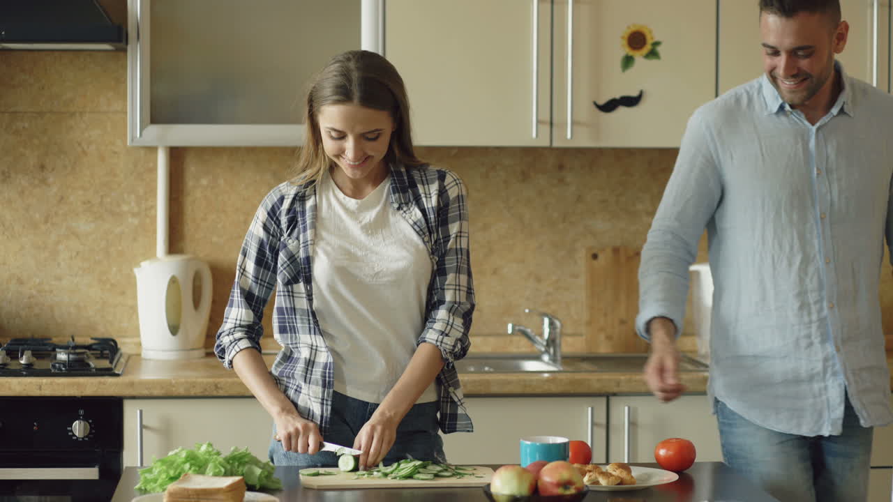 Couple Kissing and Preparing Breakfast in the Kitchen