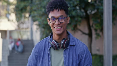 young man with headphones and laptop on campus