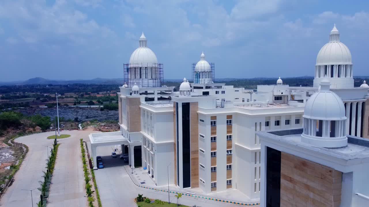 Aerial tracking shot of a grand building with large white domes under construction. Neoclassical architecture for a university or government building