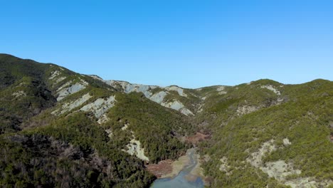 Valle-Del-Paraíso-Con-Bosques-De-árboles-Verdes-En-Las-Laderas-De-Las-Montañas-Y-Un-Lago-Tranquilo-Que-Refleja-Un-Cielo-Azul-Brillante