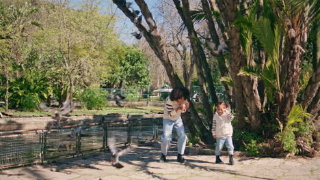 pigeons flying smiling woman with daughter in sunny park. happy family weekend