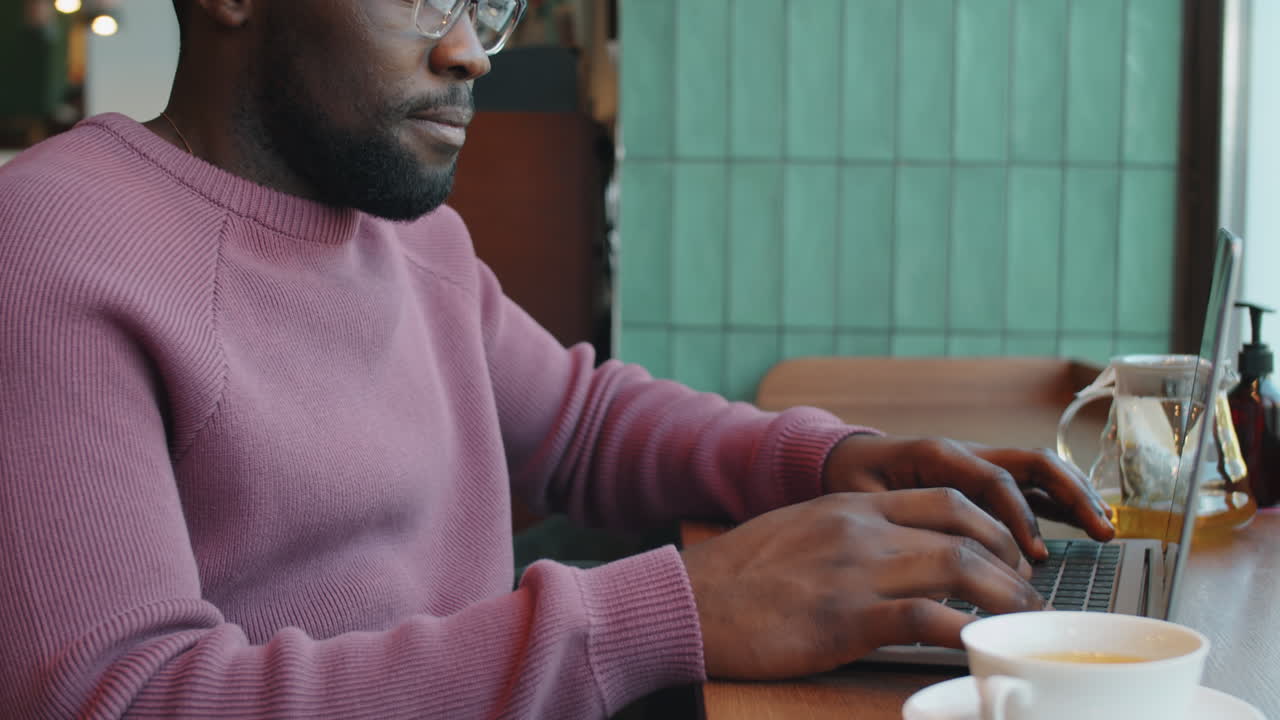 African Businessman Typing on Laptop in Cafe