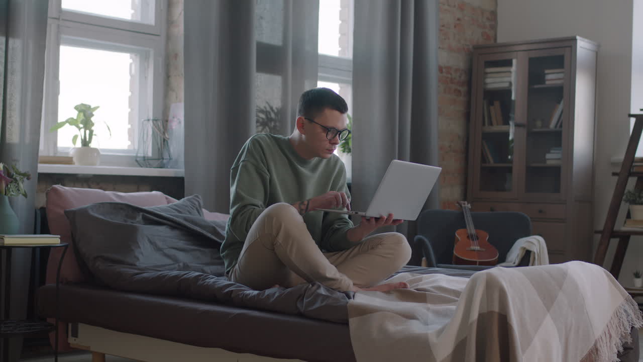 Man With Laptop Working In Bed