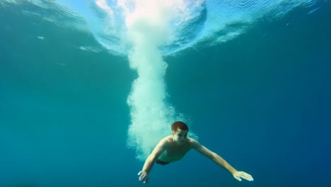 man swimming underwater with bubbles and sunlight