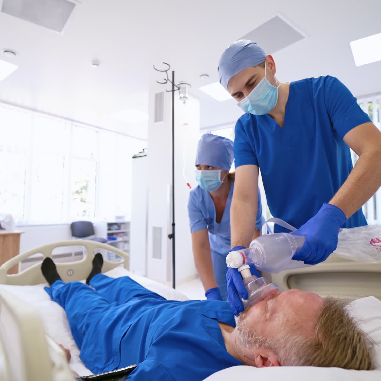 Medici che applicano una maschera d'ossigeno a un paziente in ospedale. Aiuto di primo soccorso. Sala di rianimazione. Paziente incosciente.