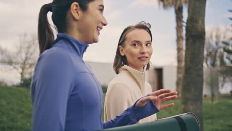 athlete ladies talking on walk spring nature. relaxed women strolling together