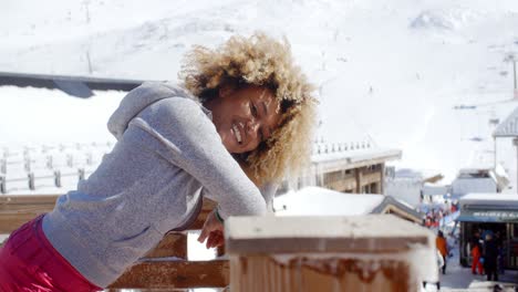 Smiling-woman-leaning-on-railing-at-ski-resort