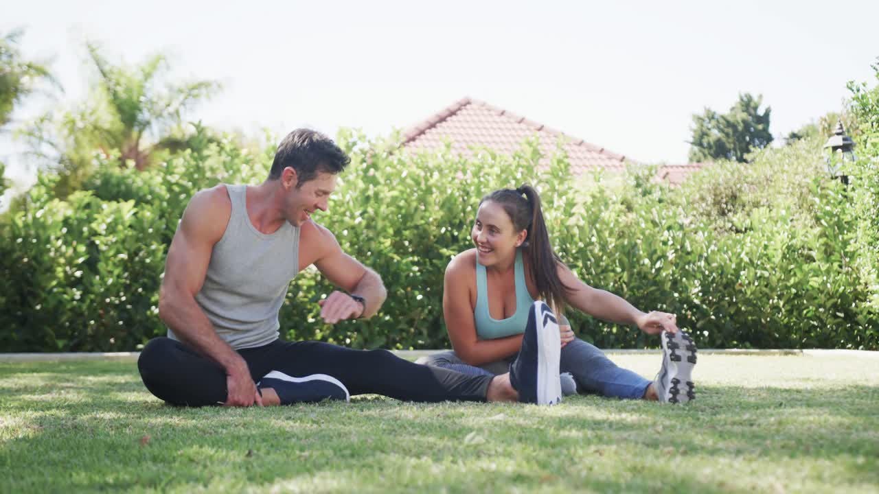 feliz pareja caucásica haciendo yoga y estirándose en un jardín soleado, cámara lenta