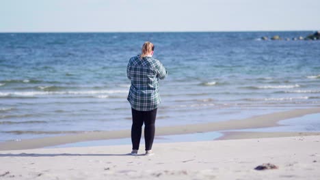 Women-standing-on-the-beach-taking-photos-of-the-ocean