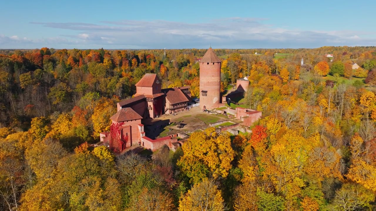 Drone che si abbassa sopra il Castello di Turaida circondato dalle foreste dorate della Valle del Gauja