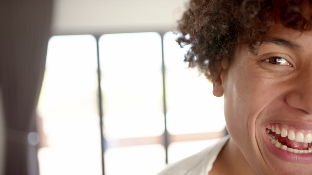 Smiling man with curly hair enjoying time at home, close-up portrait, copy space