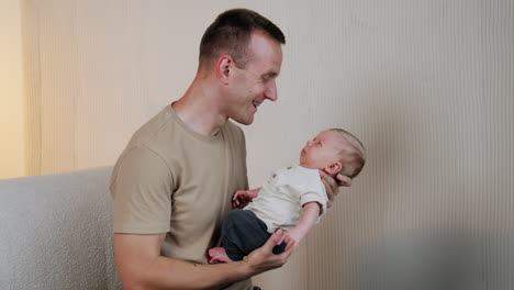 father smiles happily to his wakening newborn son. first time dad portrait. father and son at home.