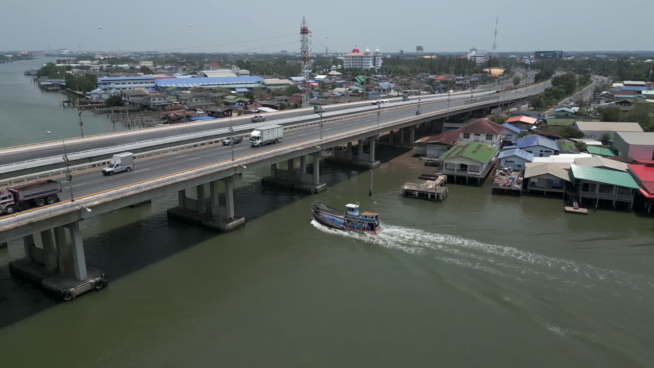 Aerial view of a major bridge over a river in an urban setting with vehicle and boat traffic