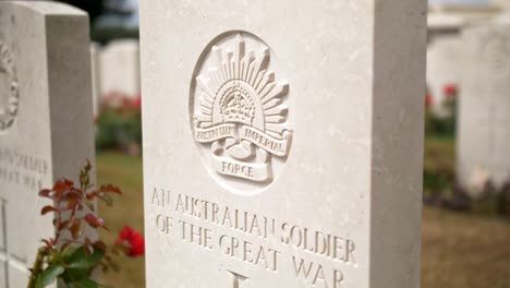 Australian-Soldier-Headstone-Grave-closeup-at-a-War-Memorial-Cemetery-amongst-a-beautiful-Green-Garden-with-Red-Roses-in-Ypres-Beglium,-sliding-handheld-shot