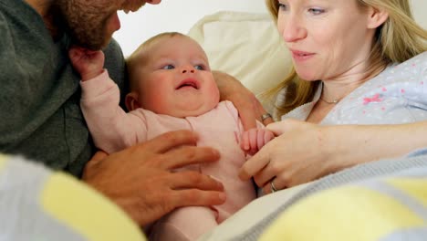 close-up of mid adult caucasian parents playing with baby on bed in a comfortable home 4k