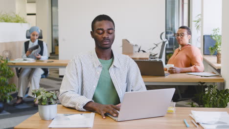 Junger-Arbeiter,-Der-Mit-Einem-Laptop-Arbeitet,-Der-An-Seinem-Schreibtisch-Sitzt-2