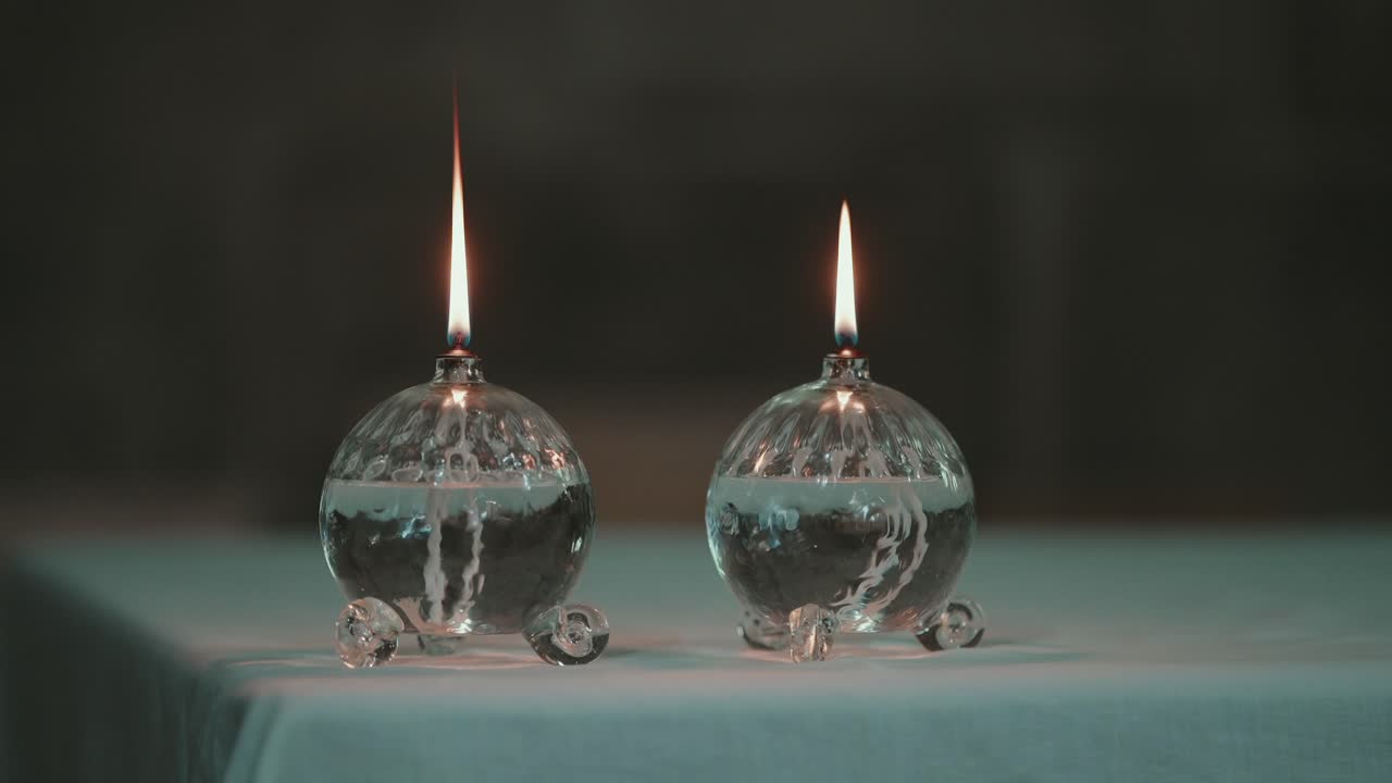 Two decorative glass oil candles burning softly