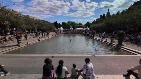family enjoying a sunny day in a city park with a pond