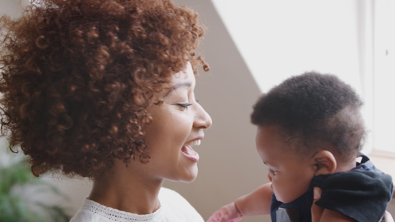 madre jugando con el hijo recién nacido y levantándolo en el aire en el apartamento del loft
