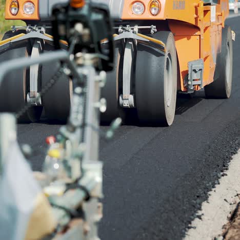 road machinery for leveling the ground passes the road under the supervision of workers. close-up