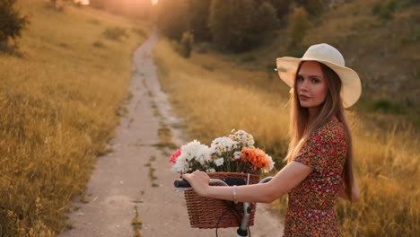 lens flare: smiling happy woman in short dress is riding a bicycle with a basket and flowers in the park with green trees around during the dawn. slowmotion shot