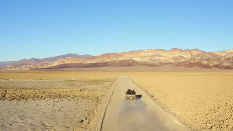 Vista-Aérea-De-Un-Solo-Jeep-Suv-En-La-Carretera-En-Medio-De-Un-Terreno-árido-Seco-Y-Caliente-Del-Parque-Nacional-Del-Valle-De-La-Muerte