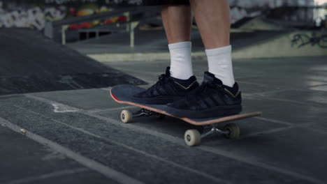 Active-man-practicing-skateboard-at-skate-park-with-graffiti-on-wall.