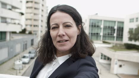 mujer de negocios alegre hablando y sonriendo a la cámara