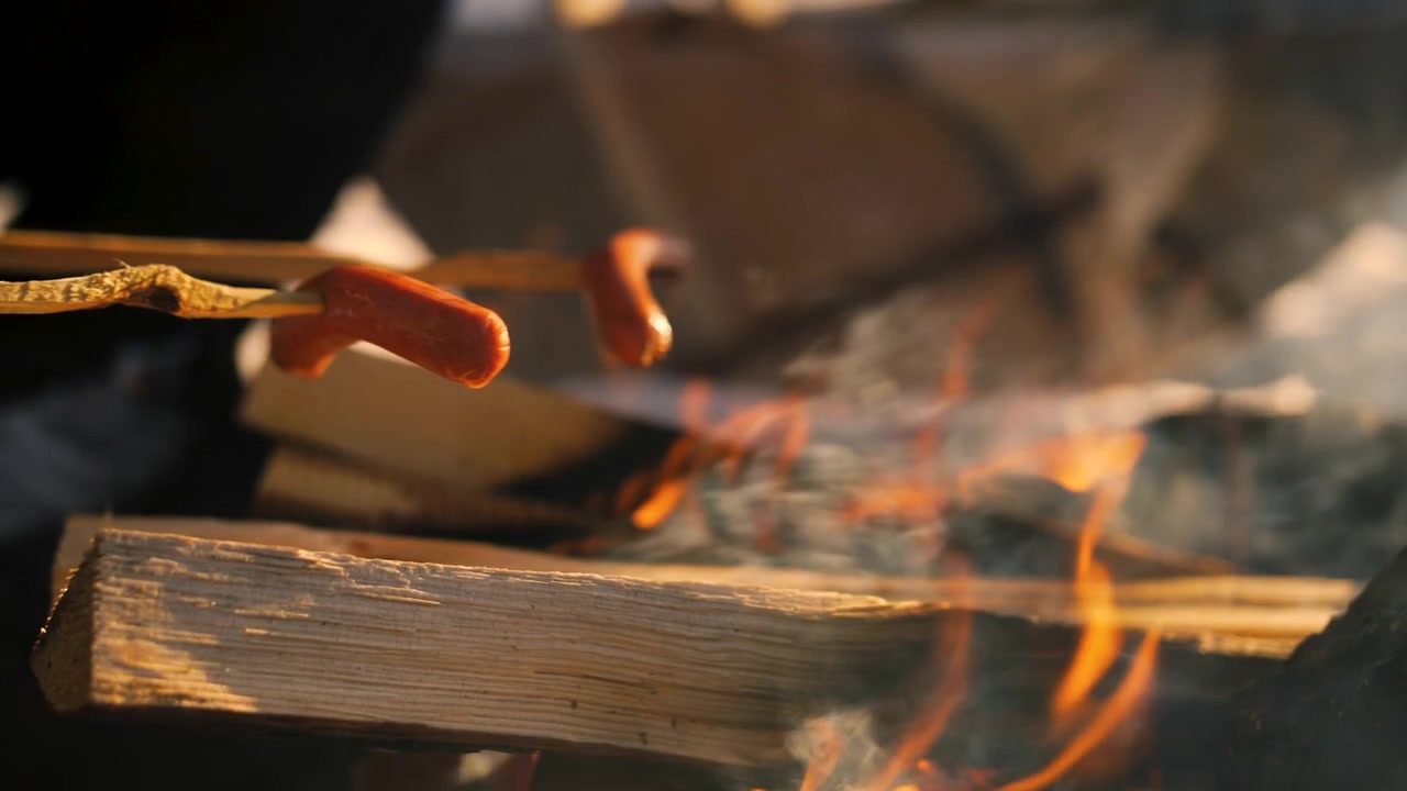 Hotdog panggang di atas api terbuka dengan tusuk buatan tangan