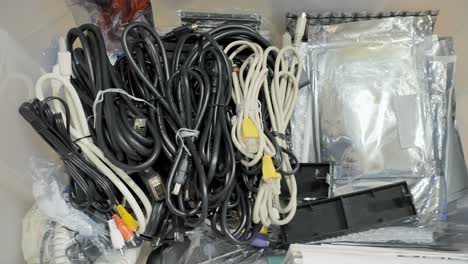 procediendo a guardar muchos cables de computadora y hifi en una caja de almacenamiento de plástico y cerrando la tapa