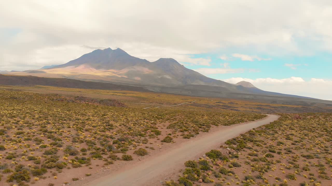 Inquadratura cinematografica d'apertura che segue una strada sterrata nel deserto di Atacama, Cile, Sud America