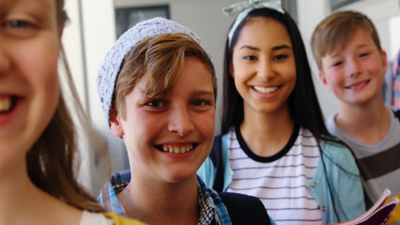 estudiantes sonrientes de pie con un cuaderno en el pasillo