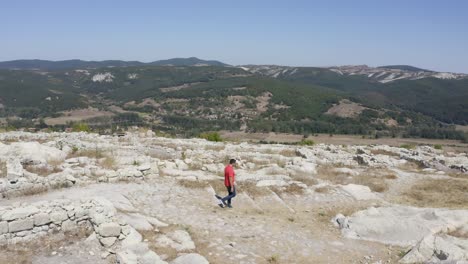 Toma-En-órbita-De-Un-Turista-Local-Caminando-Por-Las-Ruinas-De-La-Antigua-Ciudad-De-Perperikon,-Ubicada-En-La-Provincia-De-Kardzhali-En-Bulgaria.