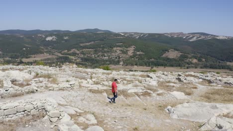 tomada de un drone en órbita de un turista local caminando por las ruinas de la antigua ciudad de perperikon, ubicada en la provincia de kardzhali en bulgaria
