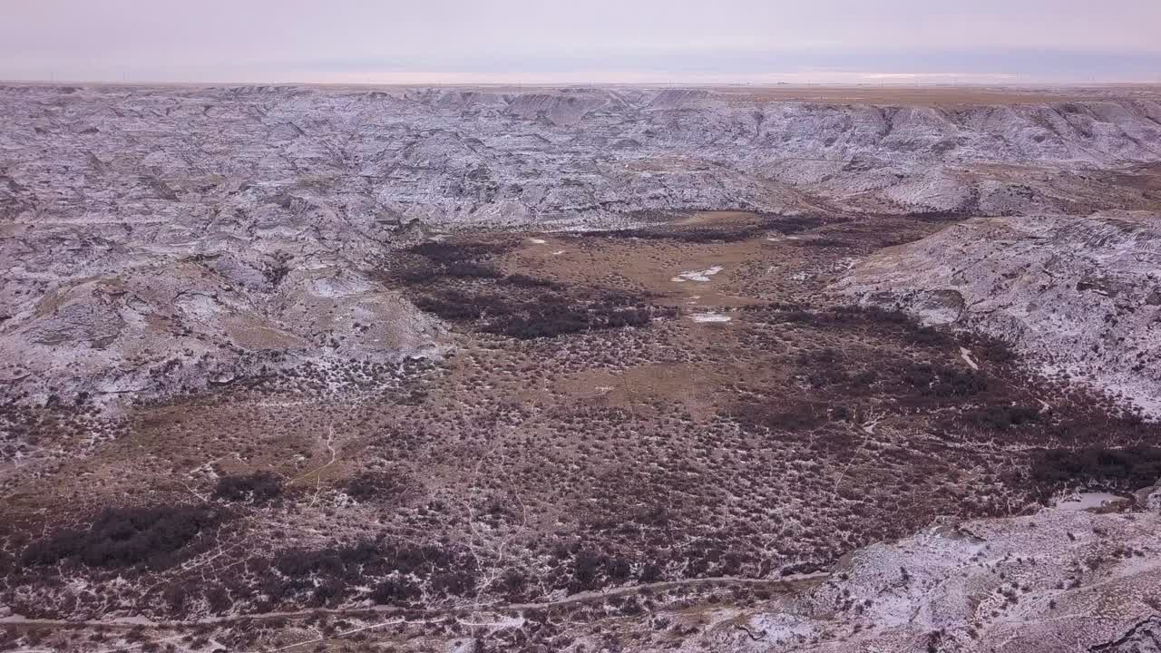 Vista aérea del fondo de un valle de malpaís entrecruzado con senderos de animales en la nieve.