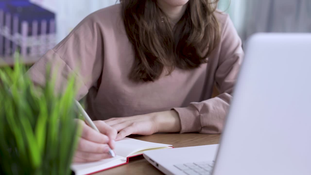 젊은 여학생이 노트북에 글을 쓰거나 그림을 그립니다.