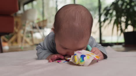 Süßes-Asiatisches-Baby,-Das-Bauchzeit-Macht-Und-Mit-Beißspielzeugen-Spielt