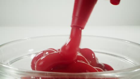 ketchup being poured into a glass bowl
