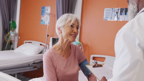 African-american-male-doctor-taking-blood-pressure-of-senior-caucasian-female-patient-at-hospital