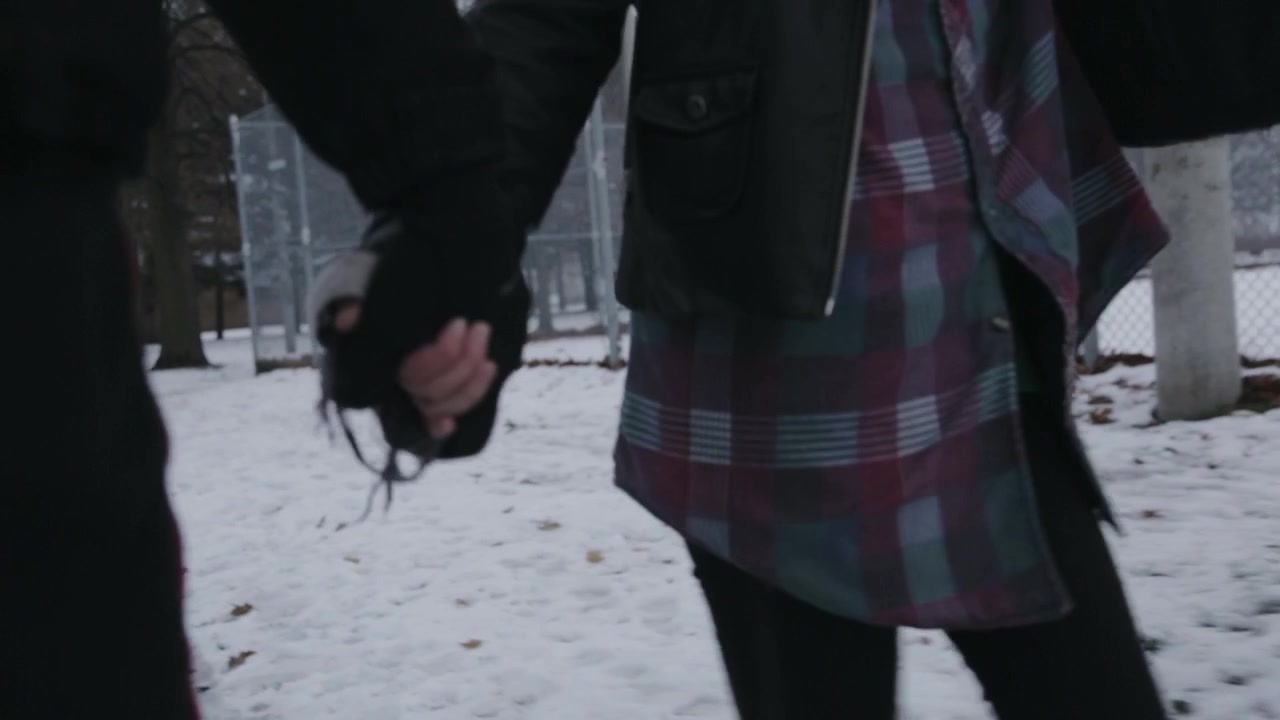 Una bambina con sua madre che camminano insieme su un sentiero innevato tenendosi per mano in una fredda giornata invernale - Primo piano.