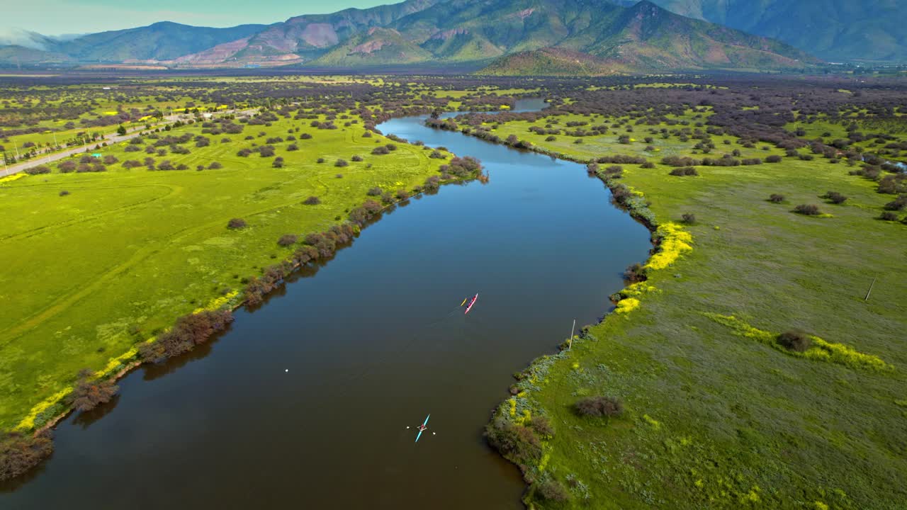 Tilt up flyover revealing the Caren Lagoon with boats on the waterway, Santiago, Chile. Sunny day in a meadow