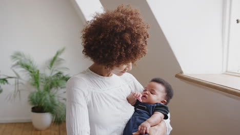 loving mother holding newborn baby son at home in loft apartment