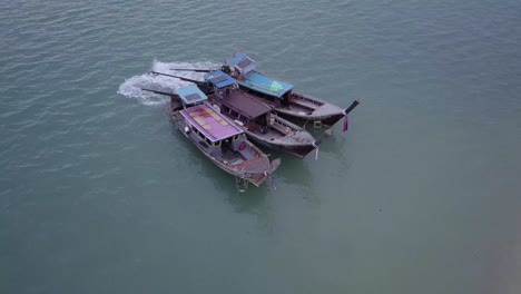 three traditional thai boats floating in the sea near the shore in phuket, thailand