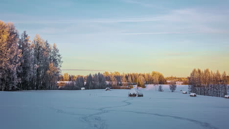 Timelapse-shot-of-white-cloud-movement-along-snow-covered-white-farmlands-with-hay-bales-surrounded-by-trees-during-evening-time