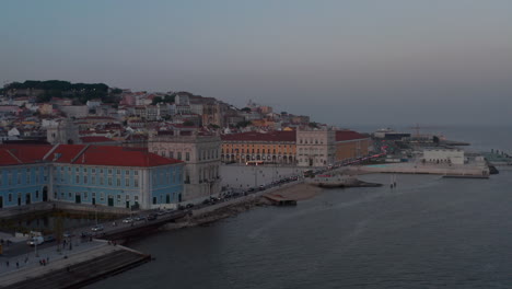 Aerial-view-of-busy-car-traffic-on-coastal-road-past-Praca-do-Comercio-square-in-Lisbon-city-center-in-evening-light