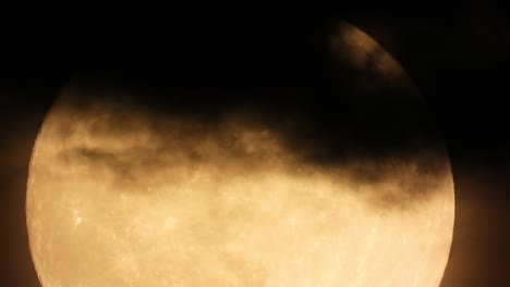 Extreme-close-up-of-Full-Moon-Moving-up-Hiding-in-Black-Clouds