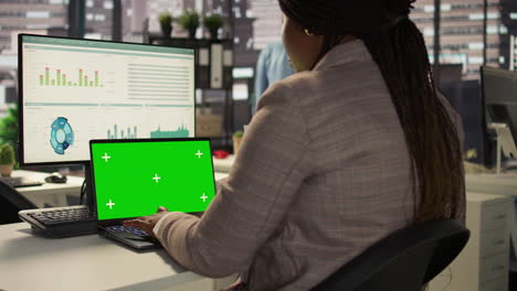 mujer de negocios trabajando en una computadora portátil con pantalla verde en una oficina