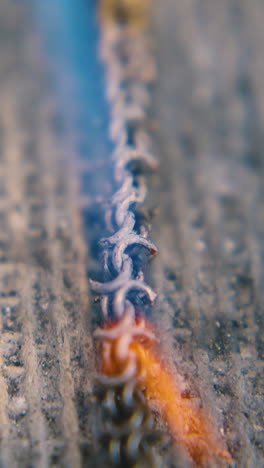 cu: professional jeweler covers gold metal chain with material and heats part with gas burner on asbestos sheet closeup